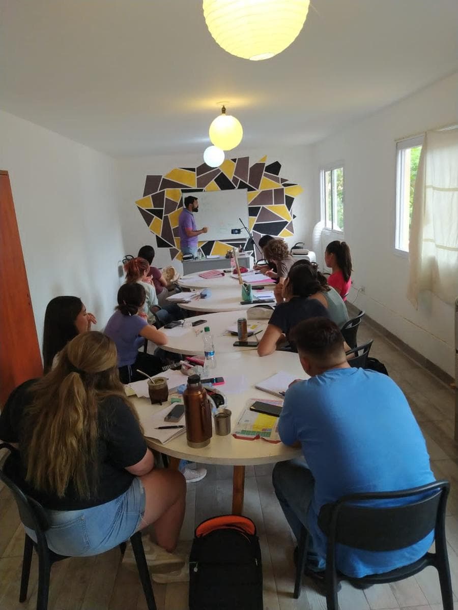 Estudiantes de SVANTE estudiando juntos alrededor de una mesa larga mientras el profesor explica en el pizarrón